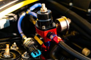 Close-up of a red fuel pressure regulator in car engine.
